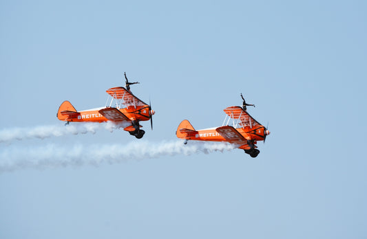 two airplanes flying in the sky with smoke trailing behind them
