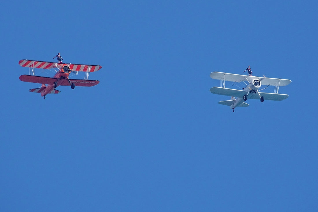 two small airplanes flying side by side in the sky