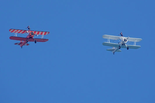 two small airplanes flying side by side in the sky