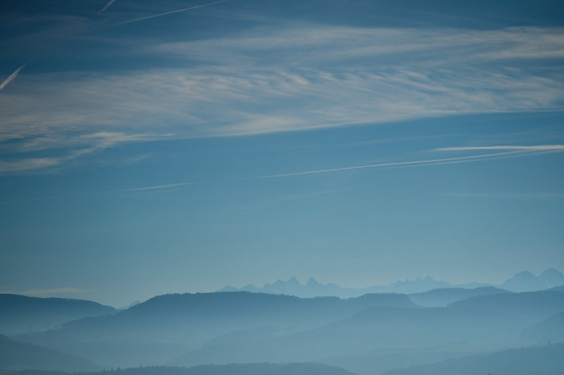 a plane flying over a mountain range under a blue sky