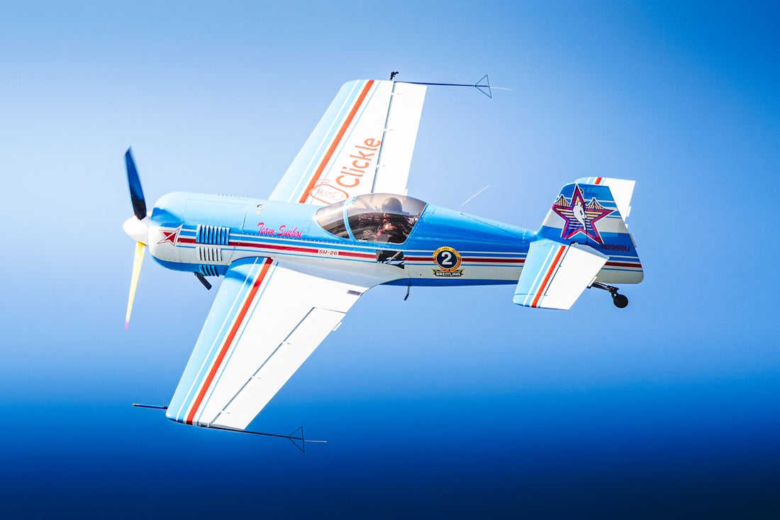 A blue and white stunt plane flying in the sky.