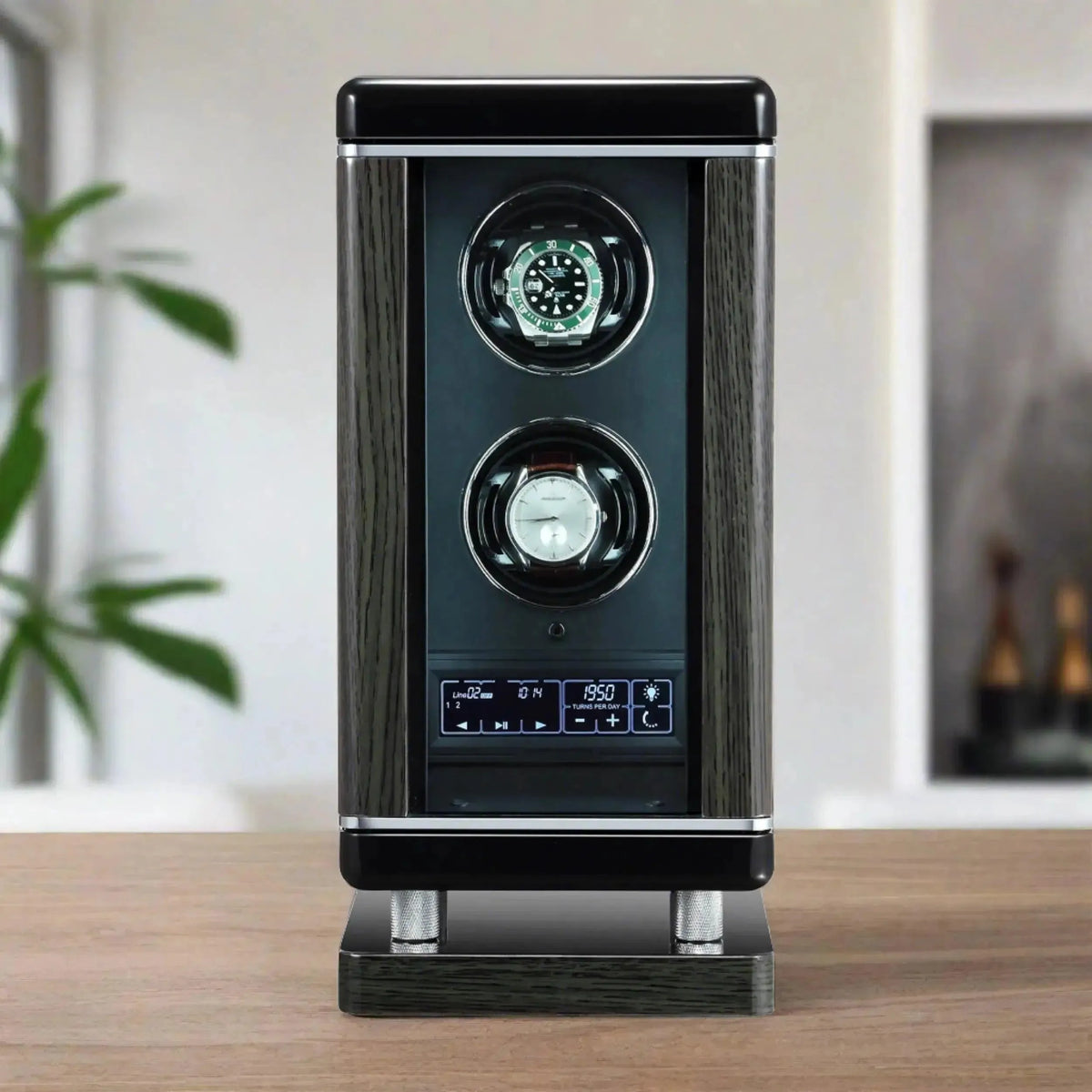 The Tempus Luxury Watch Winders 2 Watch Winder for Automatic Watches For Men with BioMetric Access Technology features a black and silver design, digital controls, and holds two watches, displayed on a wooden surface with plants and shelves in the blurred background.